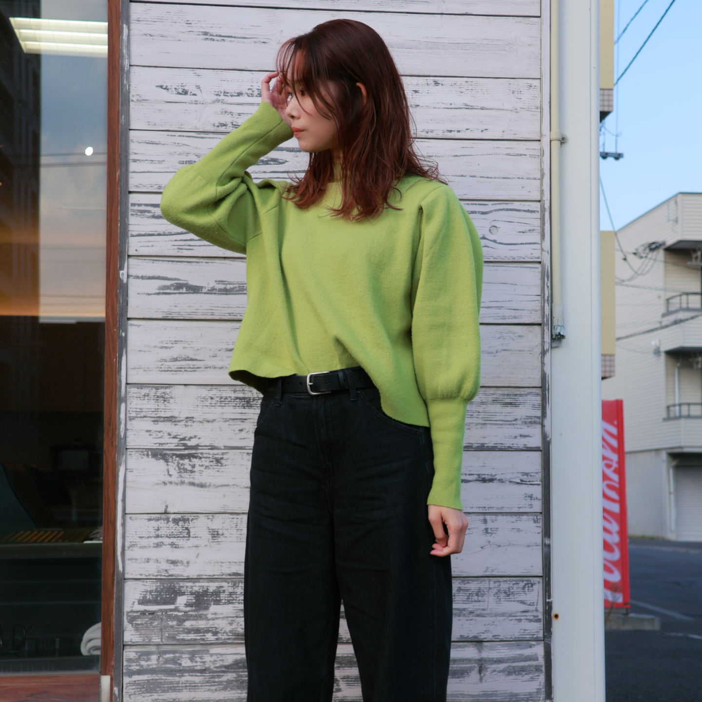 札幌市東区の美容室「ハートシェイプドボックス」のヘアスタイル作例。シンプルな白い壁を背景に、美しく整えられた髪に手をやる洗練された表情の女性。再現性の高いカットとカラー技術が光る一枚。